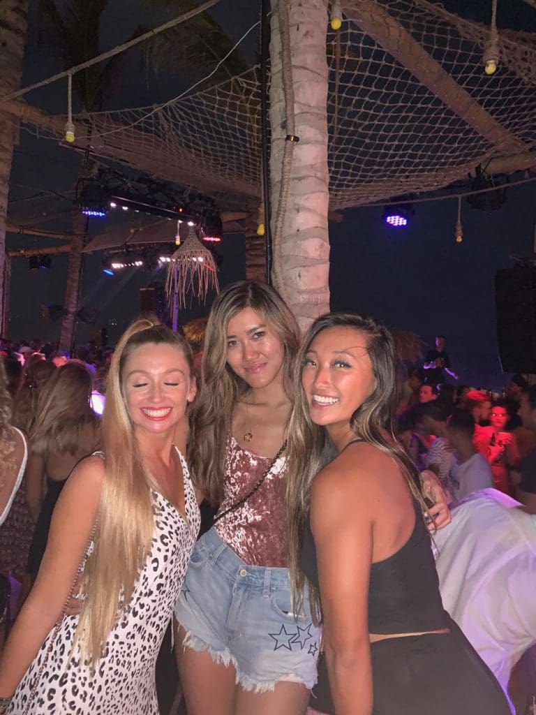 Three girls smiling at the camera at a night club