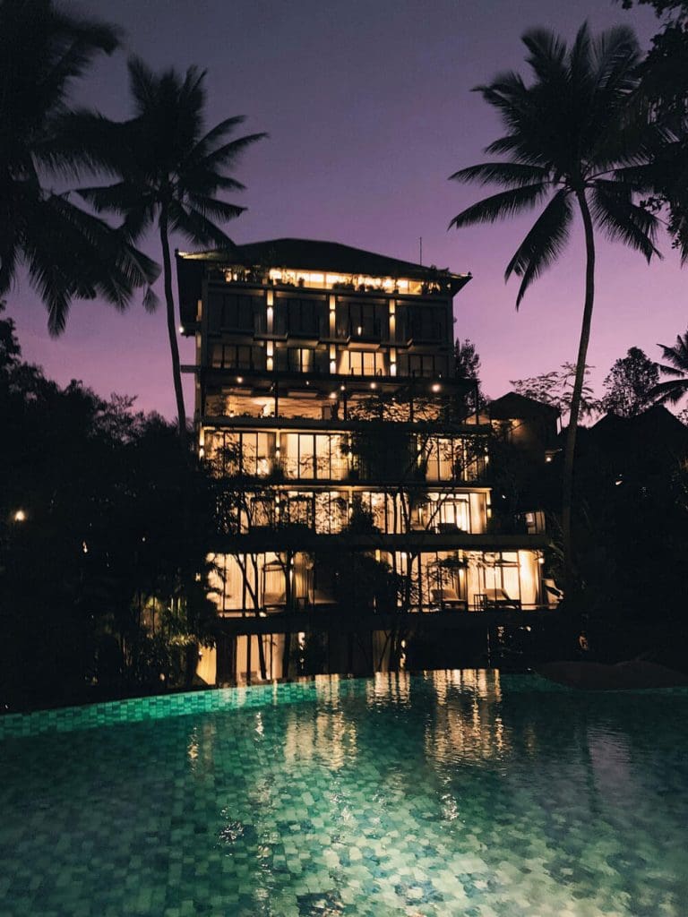 Pool at Plataran Hotel in Ubud Bali at nighttime with palm tree silhouettes