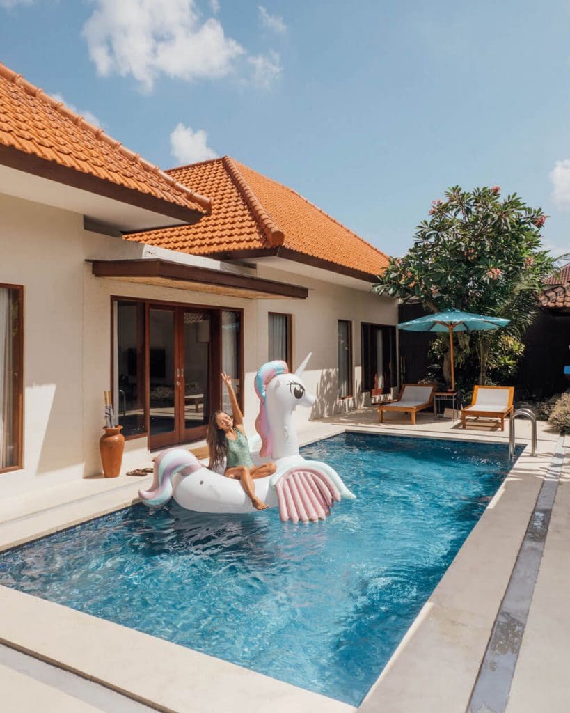 Asian girl on a unicorn floatie inside a Bali villa pool
