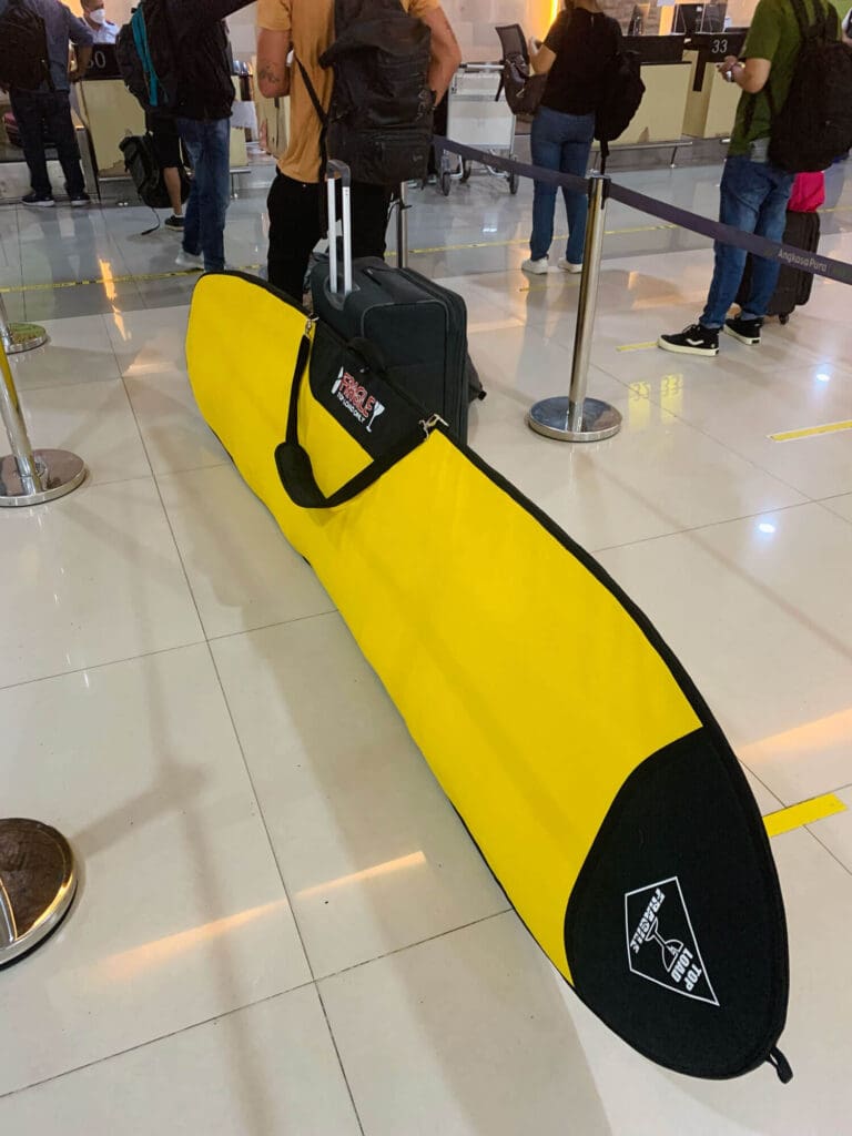 Yellow longboard surfboard bag at the airport in Kupang