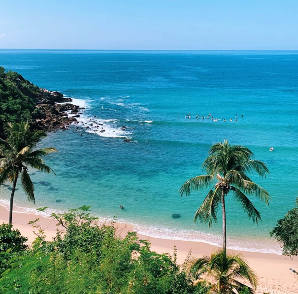 Clear blue waters in Puerto Escondido, Mexico with palm trees and surfers