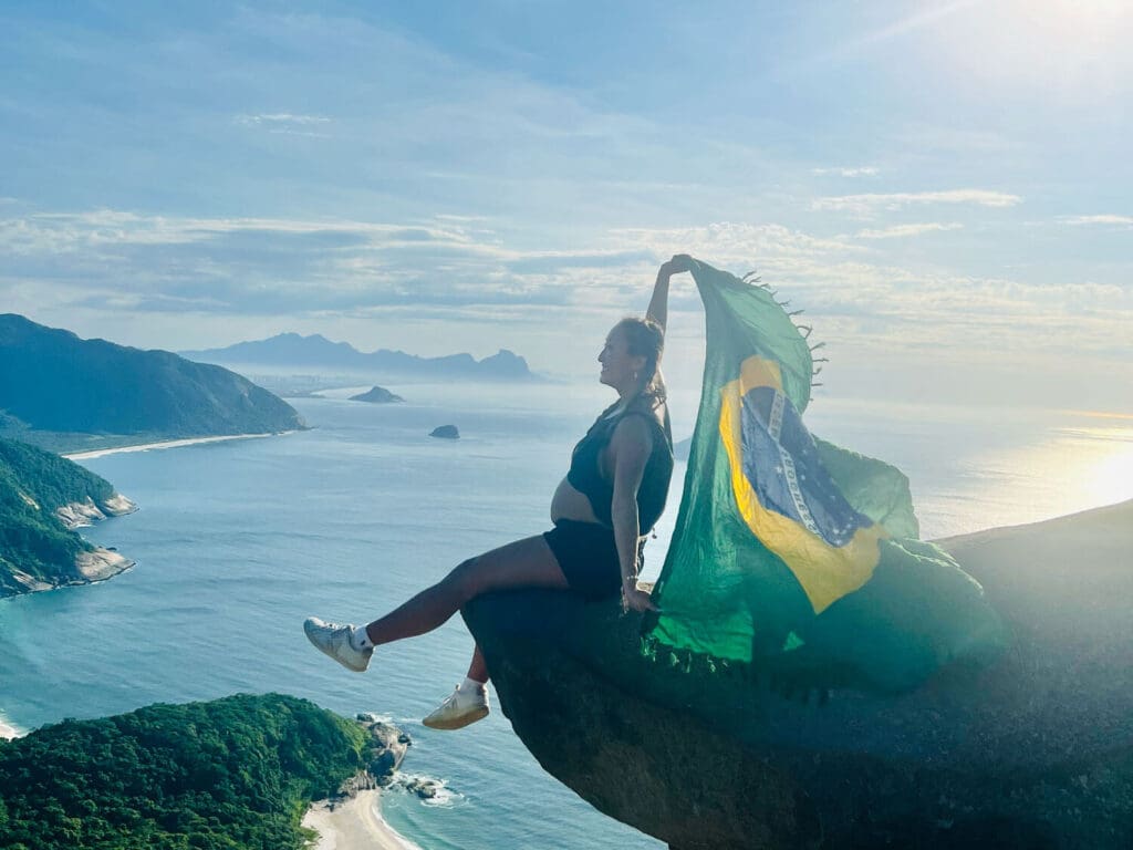 Pregnant girl sitting on the rock with a Brazil flag